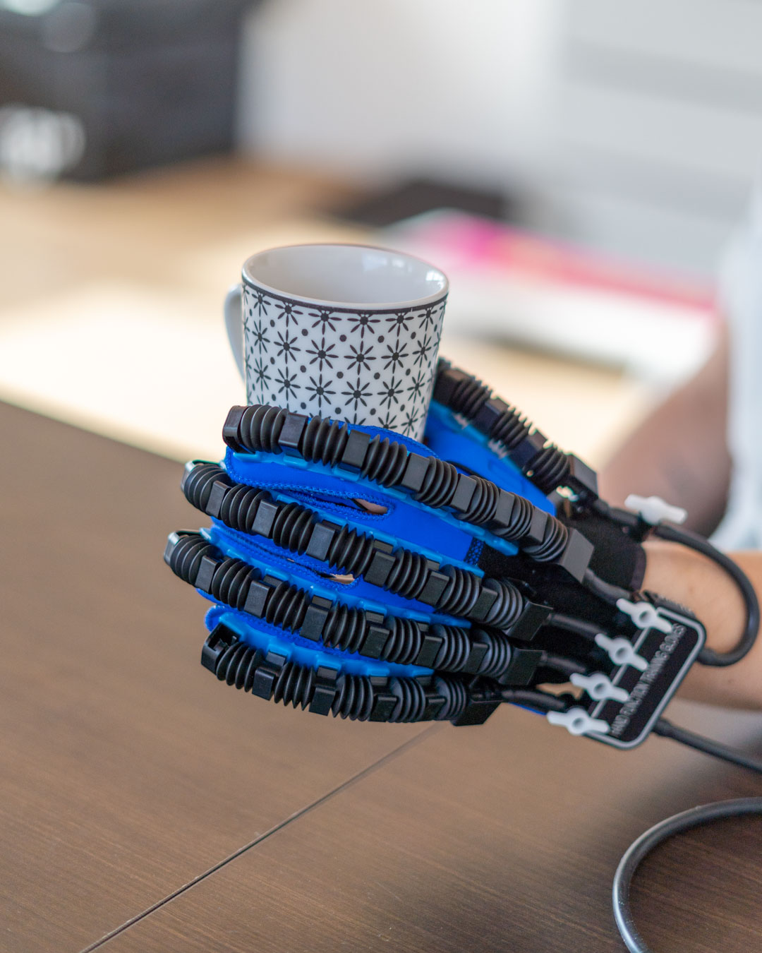 Neurorehabilitation Handfunktion Tasse Patient hält mithilfe eines motorisierten Handschuhs eine Tasse