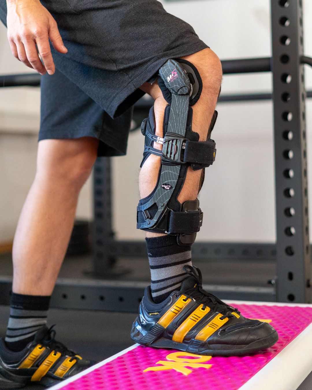 Sportphysiotherapie Schiene Stepup Ein Patient mit Kreuzbandriss in einer Schiene führt einen Step-Up durch